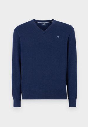 Mornarice plava v-neck džemper od mekanog pletenog materijala. Ima dugačke rukave i diskretno izvezeno logo na prsima. Glatka tekstura.