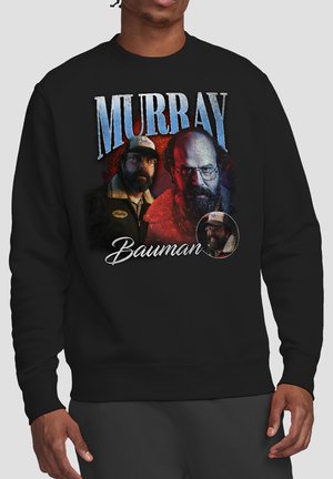 Schwarzer Sweatshirt mit drei Porträts eines bärtigen Mannes mit Brille und Mütze, darüber und darunter der Text "Murray Bauman".