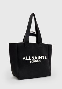 Mustakankainen kangaskassi, jossa on vahvistetut kahvat. Edessä valkoisella painettu logo "ALLSAINTS LONDON". Tyyliltään suorakulmainen ja jämäkkä muoto.