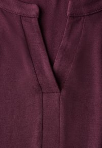 Burgunderfarbenes Strickoberteil mit V-Ausschnitt, strukturiertem Stoff und dezenten Nähdetails am Kragen und an den Seiten.