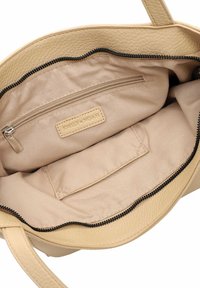 Beige synthetic tote bag interior shown with a zippered pocket and a slip pocket, featuring a textured finish and smooth lining.