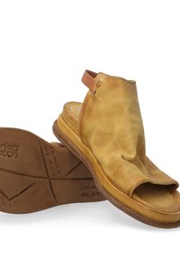 Yellow leather slingback sandals with an open toe design, wrinkled texture, and a light brown sole featuring a geometric tread pattern.