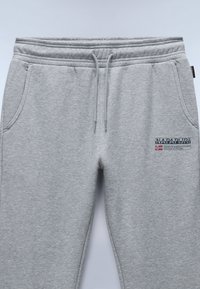 Grijze katoenen trainingsbroek met een elastische tailleband, trekkoord, zijzakken en een logopatch op de dij. Soepele textuur, taps toelopende pasvorm.