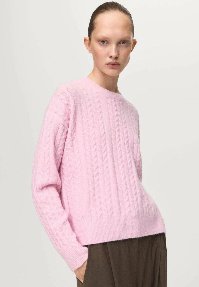 Maglione rosa a maglia rasata con scollo rotondo e fondo a costine. Texture morbida, maniche lunghe, motivo lavorato a maglia dettagliato, abbinato a pantaloni marroni.