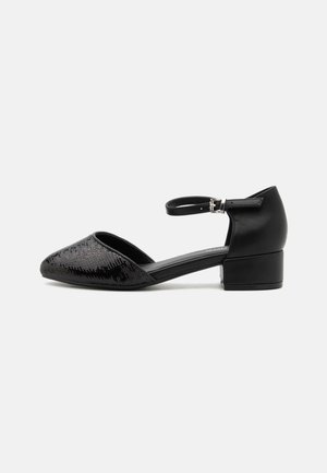 Black ankle strap shoe with a pointed toe, featuring a textured upper and a low block heel for stability. Material is a mix of soft leather and synthetic fabric.