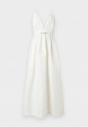 Robe longue blanche sans manches avec col en V profond, fines bretelles, taille froncée et ornement décoratif au centre devant.