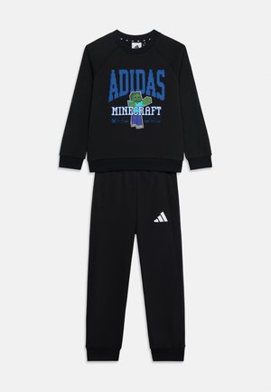 Czarny dres dziecięcy Adidas z grafiką Minecraft przedstawiającą pikselowaną postać na bluzie oraz białe logo Adidas na spodniach.