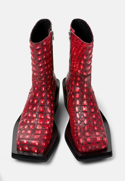 Paire de bottines rouges en cuir à texture de crocodile, avec bouts carrés, fermetures éclair latérales et semelles épaisses noires à plateforme.