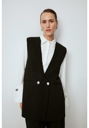 Black vest with a deep V-neck, featuring pearl button closures and a decorative black bead trim, layered over a white collared shirt.