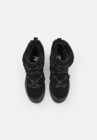 Botas de tobillo de ante negro con borde de piel sintética, punta redonda y cordones grises. Presentan una suela de goma texturizada y un talón reforzado para mayor durabilidad.