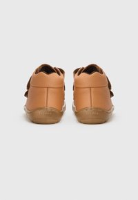 Bruine leren schoenen met een gestructureerd oppervlak en een zachte bruine voering. Platte rubberen zolen met 'froddo' branding, ontworpen voor comfort en duurzaamheid.