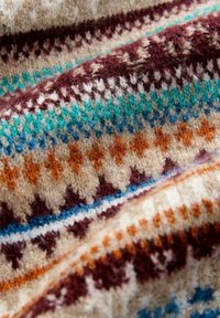 Weiches gestricktes Gewebe mit geometrischen Mustern in Orange, Petrol, Braun und Beige, das Nahaufnahmen von Textur und Farbdetails zeigt.