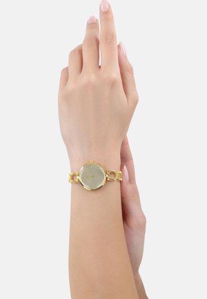 Goldene Uhr mit rundem Ziffernblatt, silbernem Ziffernblatt und goldener Gliederarmband. Glatte Textur, minimale Stundenmarkierungen, elegantes Design.