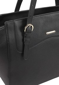 Sac à main en cuir noir avec une finition texturée, doté de poignées courtes, de quincaillerie dorée et d'un logo de marque subtil.