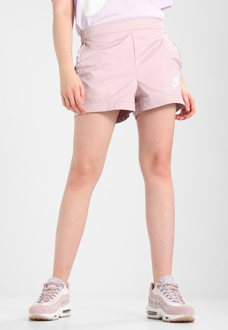 Helle rosa Nike Sportshorts mit elastischem Bund, seitlichen Streifen und Logo-Details. Glattes Material und knielange Schnittform.