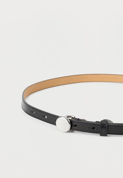 Μαύρη δερμάτινη ζώνη με λεία υφή, με ασημένια κυκλική αγκράφα και πολλαπλές τρύπες ρύθμισης. Η εσωτερική πλευρά είναι καφέ ανοιχτόχρωμη.