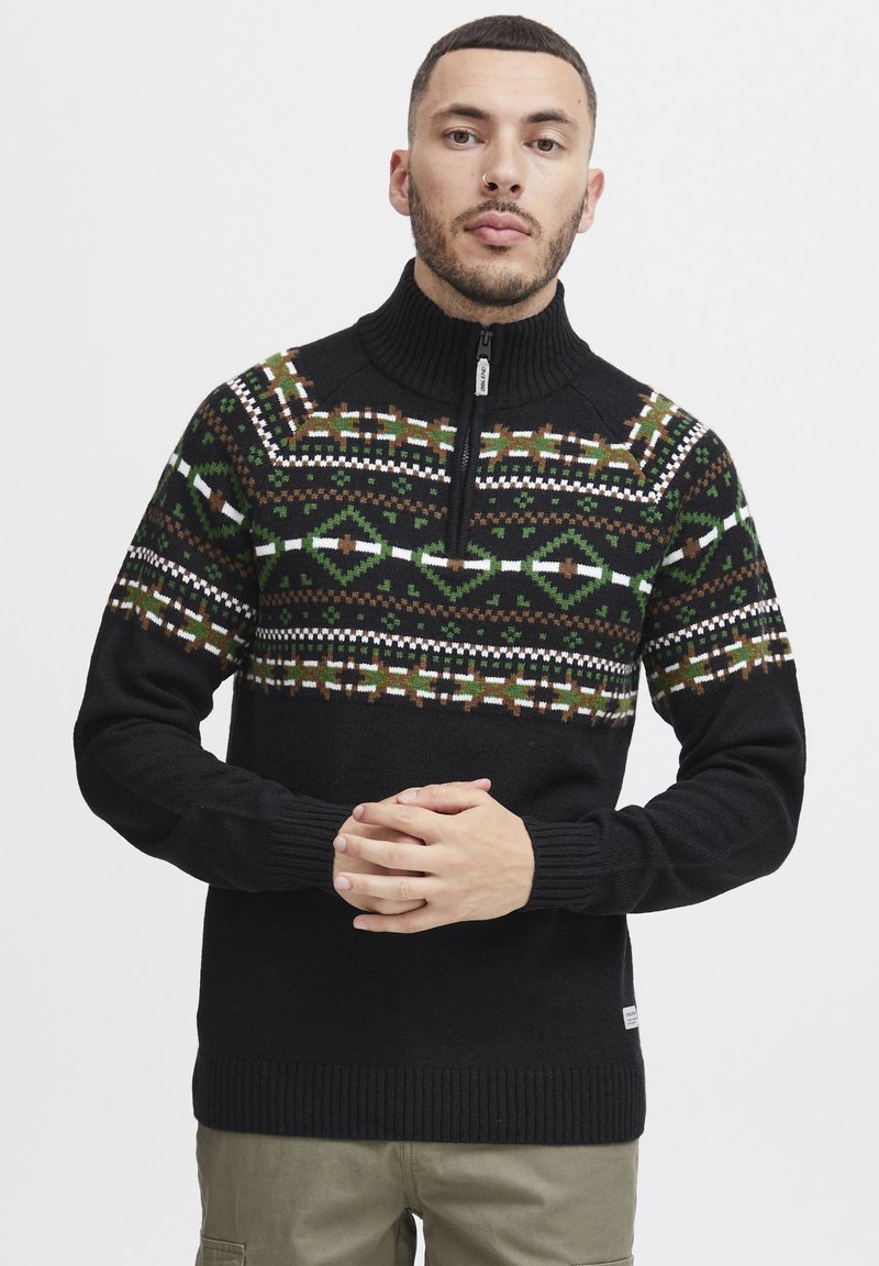 Schwarzer Pullover mit Reißverschluss und geometrischem, gemustertem Design in Grün, Braun und Weiß. Strukturierter Strickstoff mit gerippten Bündchen.