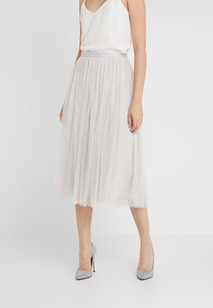 Gonna midi in tulle grigio chiaro con pieghe e piccole pois bianche, abbinata a un top bianco senza maniche e scarpe con tacco alto argentate.