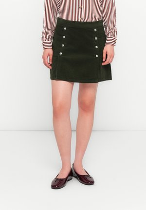 Jupe mini en velours côtelé vert foncé avec une silhouette droite, comportant six boutons en argent sur le devant et deux poches latérales.