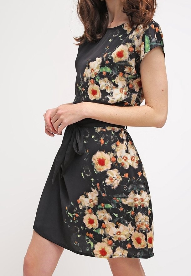 Vestido envolvente de flores en tejido negro, con mangas cortas y cintura con lazo. El diseño presenta grandes flores color crema con centros rojos y acentos verdes.