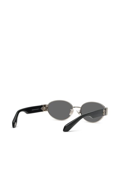 Lunettes de soleil de forme ovale avec des verres gris foncé, une monture fine en métal argenté et des branches noires incurvées.