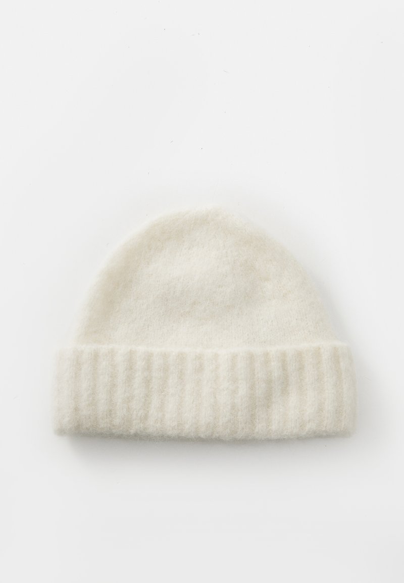 Beanie bianco in maglia realizzato in morbida lana, con un polsino a coste e una superficie liscia e leggermente pelosa, progettato per calore e comfort.