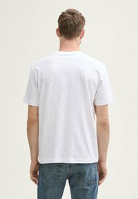 Hvid kortærmet t-shirt, crew neck design, blød tekstur, ensfarvet finish uden synlige mønstre, parret med blå denim jeans.