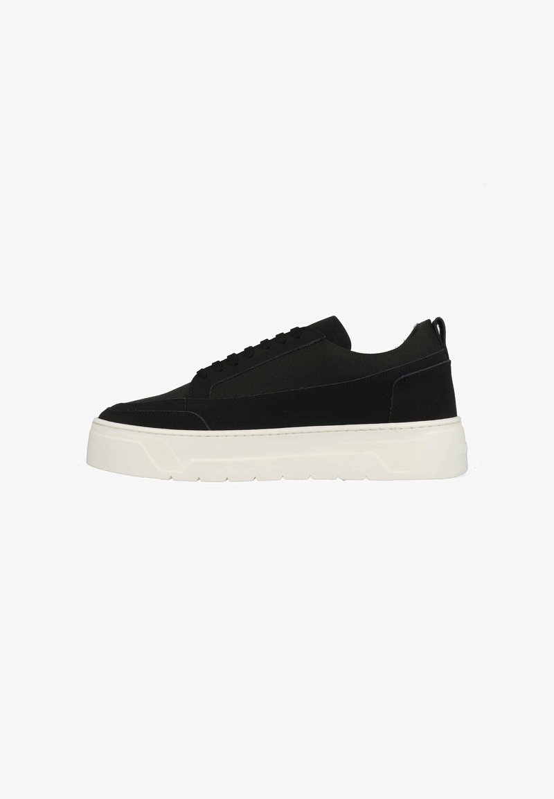 Zwarte canvas sneakers met een gestroomlijnd ontwerp, voorzien van een dikke witte rubberen zool, vetersluiting aan de voorkant en textuurpanelen aan de zijkant.