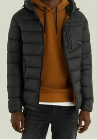 Sort puffed jakke med hætte, foret tekstur, frontlynlåse og en brystlomme, båret over en brun hoodie med snore.