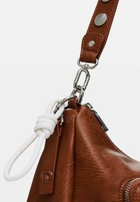 Braune Lederhandtasche mit strukturierter Oberfläche, ausgestattet mit einem weißen Knotenakzent und silberfarbener Hardware, einschließlich eines Reißverschlusses und Clip-Vorrichtungen.