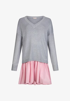 Szary sweter z długim rękawem w serek z prążkowanymi mankietami, nałożony na różową, rozkloszowaną spódnicę. Miękka tekstura, casualowy design.