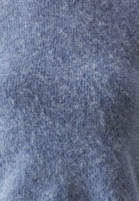 Hellblauer Pullover aus weichem, flauschigem Material. Verfügt über eine strukturierte Oberfläche mit einem subtilen Melange-Muster. Keine sichtbaren Beschläge oder Akzente.