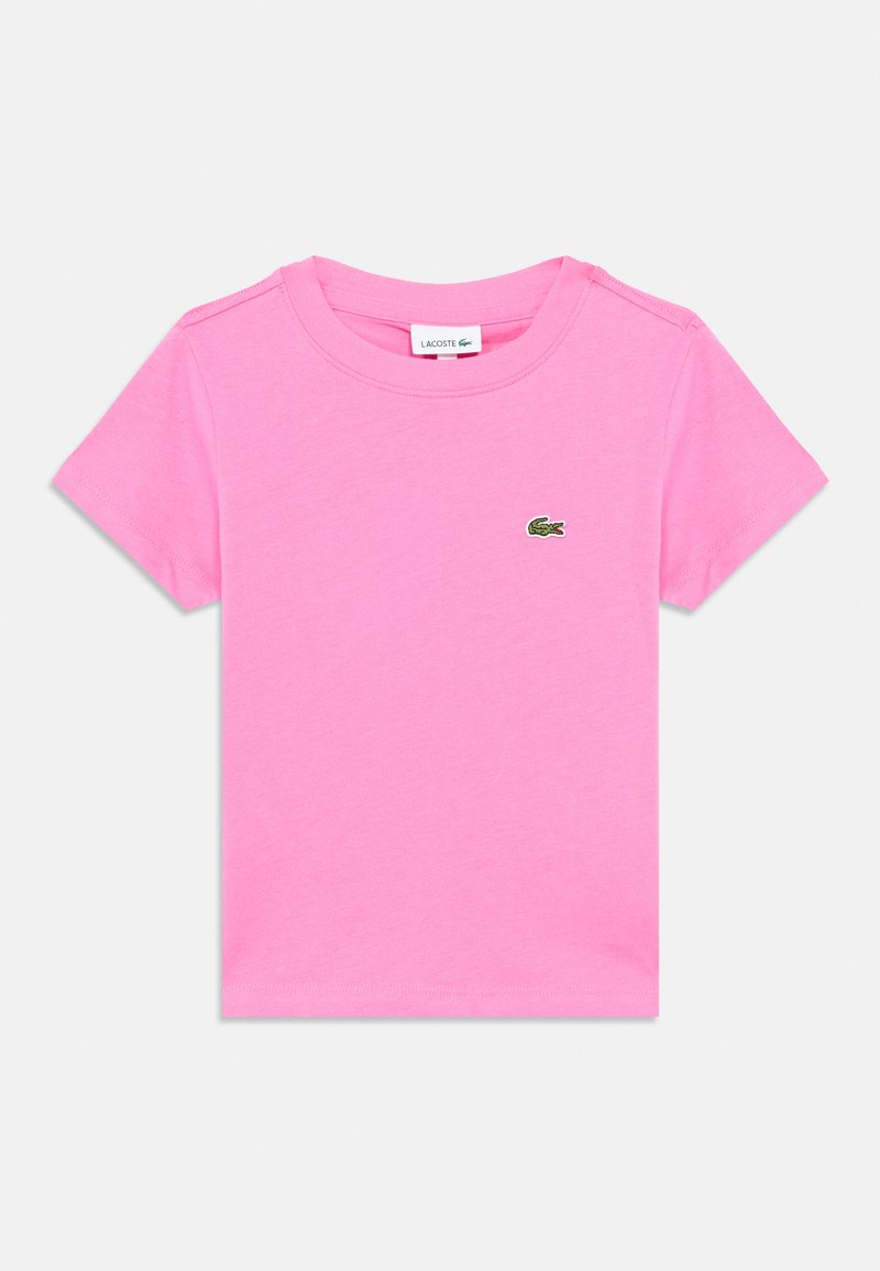 Ροζ βαμβακερό μπλουζάκι με κοντά μανίκια, στρογγυλή λαιμόκοψη και κεντητό πράσινο λογότυπο κροκοδείλου στο στήθος. Απλός, λιτός σχεδιασμός.