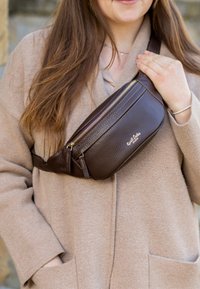 Borsa a tracolla in pelle marrone con finitura testurizzata, due scomparti con zip e logo dorato. Indossata a tracolla.