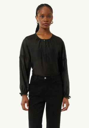 Schwarze Bluse mit langen Ärmeln, rundem Ausschnitt, Knopfleiste, strukturiertem Stoff und gerafften Manschetten, kombiniert mit hochgeschnittenen schwarzen Jeans.