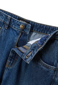 Jean en denim bleu avec une coupe classique. Présente un bouton en métal, une fermeture éclair et des coutures contrastées. L'étiquette indique "MONOPRIX."