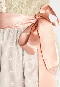 Robe vert clair avec un haut texturé aux motifs floraux, un ruban de taille en satin rose, et une jupe transparente décorée avec des fleurs brodées.