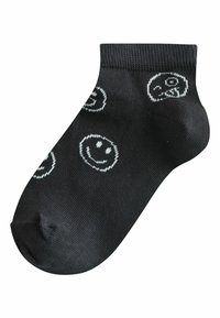 Chaussette noire à la cheville avec des motifs de visages souriants blancs répartis uniformément sur le tissu.