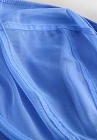 Lyseblåt netstof med fint gittermønster og glat tekstur. Kanterne har syede sømme, der skaber kontur og stabilitet.