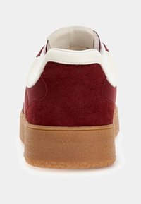 Red suede sneaker with white accents, rubber sole, and padded collar. Textured rear and smooth side panels, featuring a simple design.