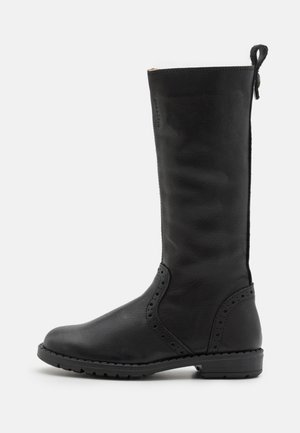 Botte noire en cuir jusqu'au genou avec un bout arrondi, des accents perforés décoratifs et une semelle en caoutchouc robuste. Dispose d'une languette en haut.