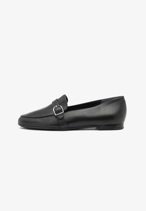 Mocassin plat en cuir noir avec détail de bride à boucle argentée et bout carré, vu de côté sur fond blanc.