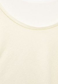 Top beige chiaro con una superficie liscia, scollo rotondo e una leggera lucentezza, sovrapposto a un tessuto bianco. Design semplice e minimale.