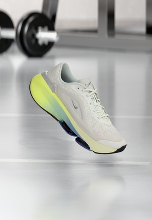 Light grey athletic shoe with a textured upper, featuring a gradient outsole in yellow and blue, and a white midsole.