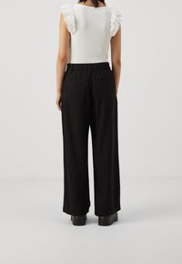 Svarta vida byxor med resårmidja, som har en slät tygfinish. Synliga bakfickor ger praktiska detaljer.