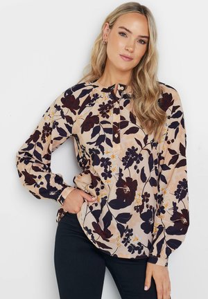 Blusa de manga larga floral en crema con flores en rojo oscuro y amarillo, que presenta un placket abotonado y un corte relajado, hecha de una tela suave.