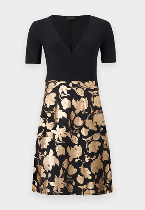 Robe portefeuille noire à manches courtes. Le corsage est entièrement noir, tandis que la jupe présente des motifs floraux dorés sur fond noir.