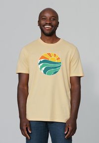 Gelbes Baumwoll-T-Shirt mit einem kreisförmigen Design, das eine orange Sonne und türkisfarbene Wellen zeigt. Kurze Ärmel und Rundhalsausschnitt.