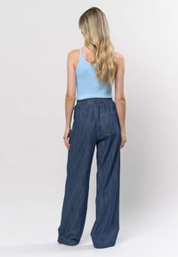 Maiou bleu deschis cu dungi, asortat cu pantaloni largi din denim albastru închis. Pantalonii au talie elastică și buzunar lateral.