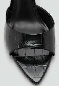 Sandal de tacón de charol negro con puntera puntiaguda, textura con relieve de cocodrilo y una banda ancha en el empeine. Forro interior suave.